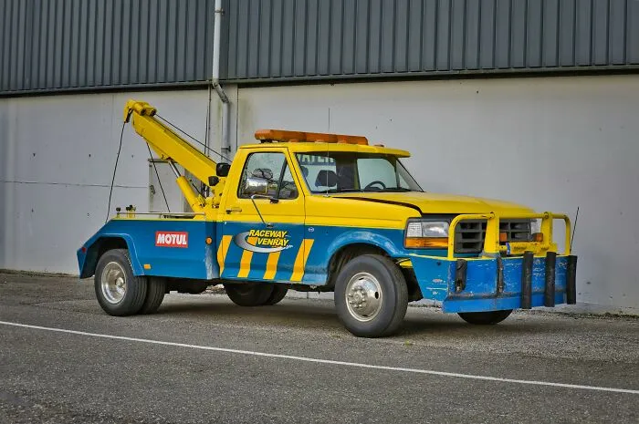 Tow truck parked outside a building, illustrating one of the professions people think attract the most awful people.