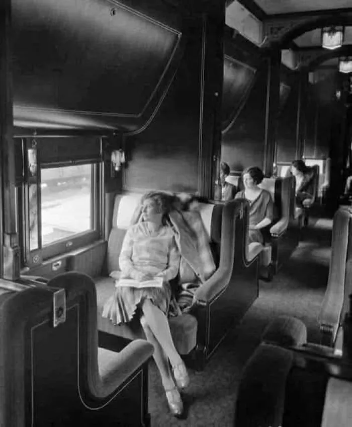 Mujer sentada en un tren antiguo mirando por la ventana, mostrando un lado distinto de la historia en una fotografía vintage.