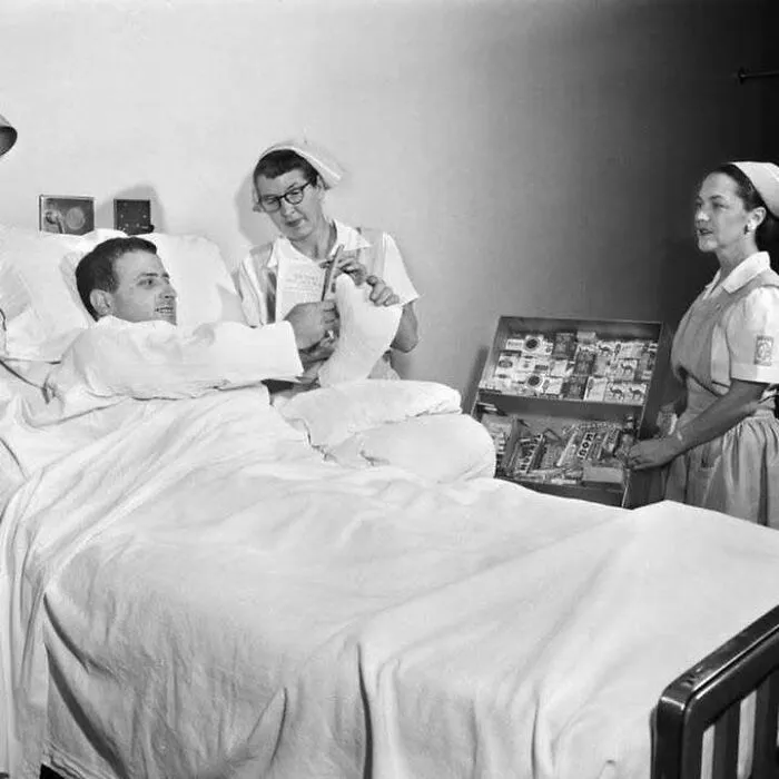 Un paciente comprando cigarrillos desde su cama de hospital, década de 1950