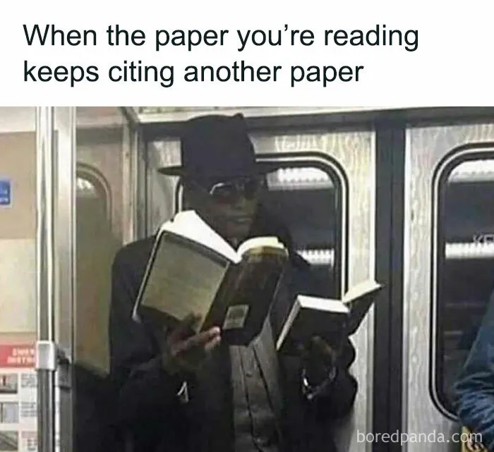 Man wearing sunglasses and a hat reading two books on a subway, illustrating intellectuals chuckling at memes.