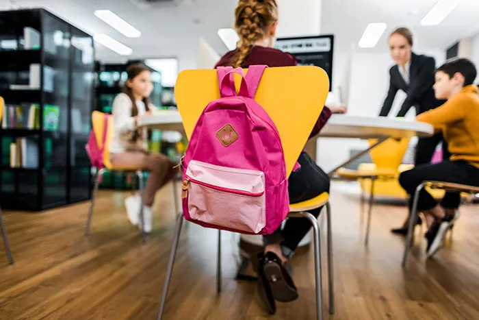 Children sitting in a classroom with backpacks, illustrating kids' lies that started off silly and got way too real.