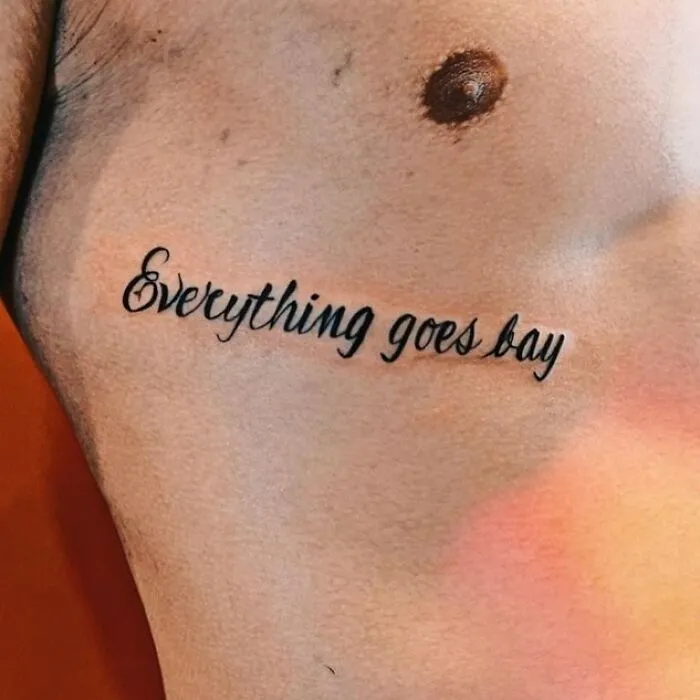 Tattoo of misspelled phrase everything goes bay inked on bare skin showing bizarre choices in tattoos.