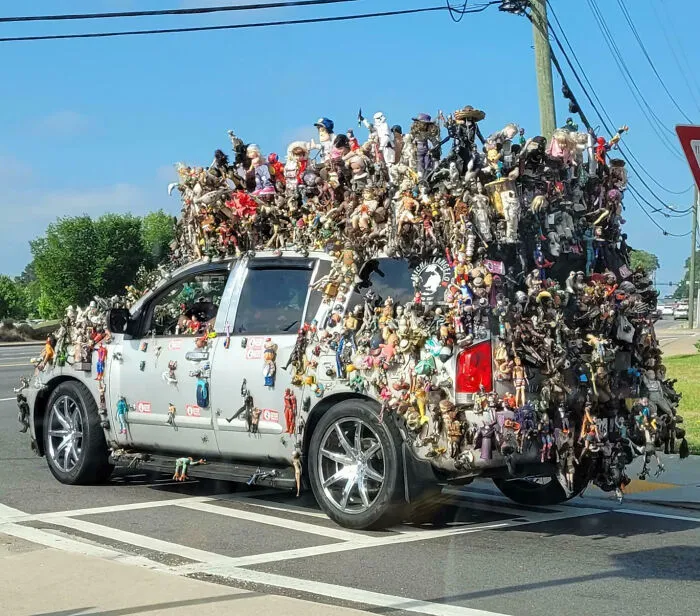 SUV covered in hundreds of action figures and dolls as an outrageous car mod on a city street.