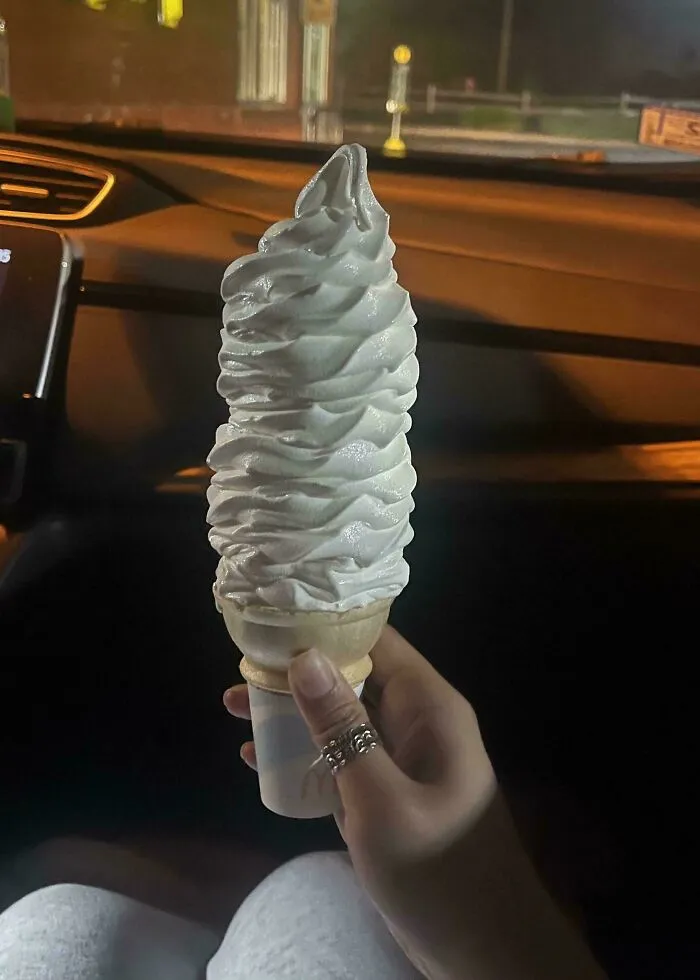 Hand holding an unusually tall soft serve ice cream cone, a mildly interesting food sight to share.