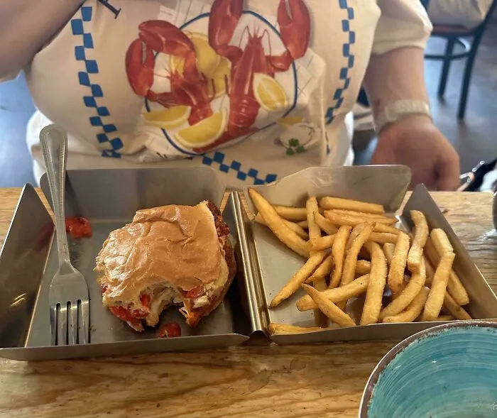 Metal tray serving a half-eaten burger and fries shown as an unholy meal presentation.