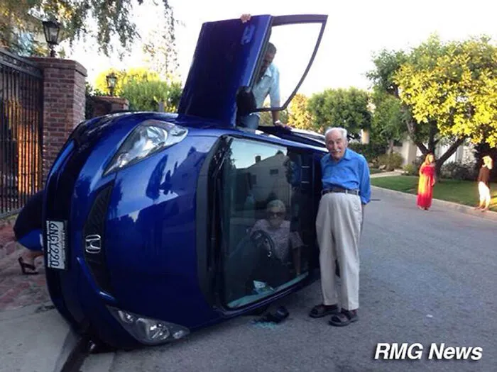 Una pareja de ancianos posa para una foto tras volcar su coche (la esposa sigue atrapada en el interior)