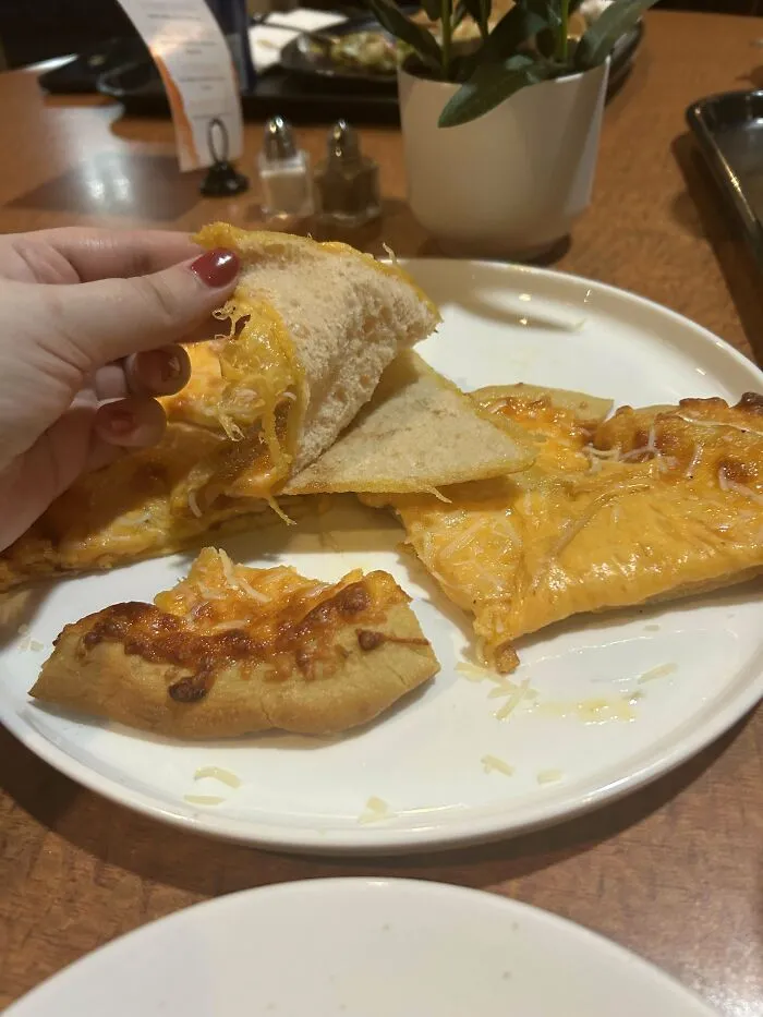 Person using a tortilla chip to lift a slice of cheese pizza, illustrating a funny unfortunate situation with food.
