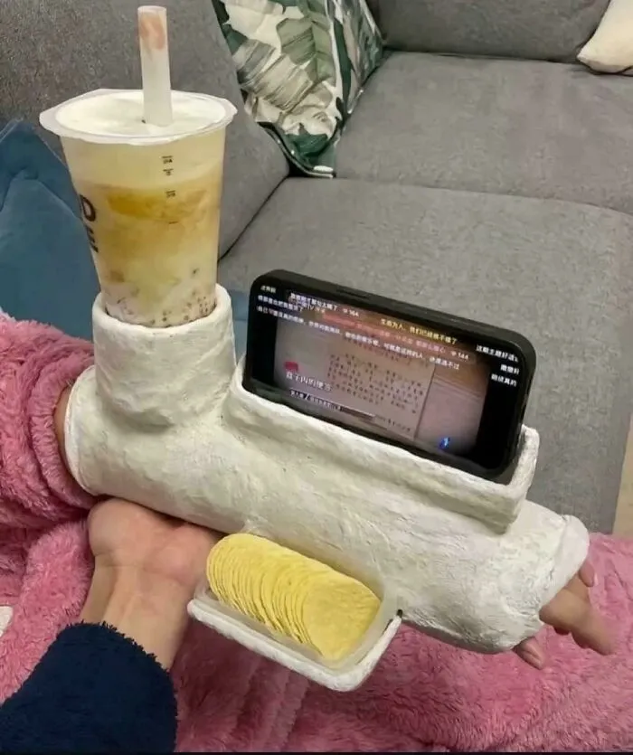 Arm-mounted redneck engineering device holding a bubble tea, smartphone, and snacks for hands-free convenience.
