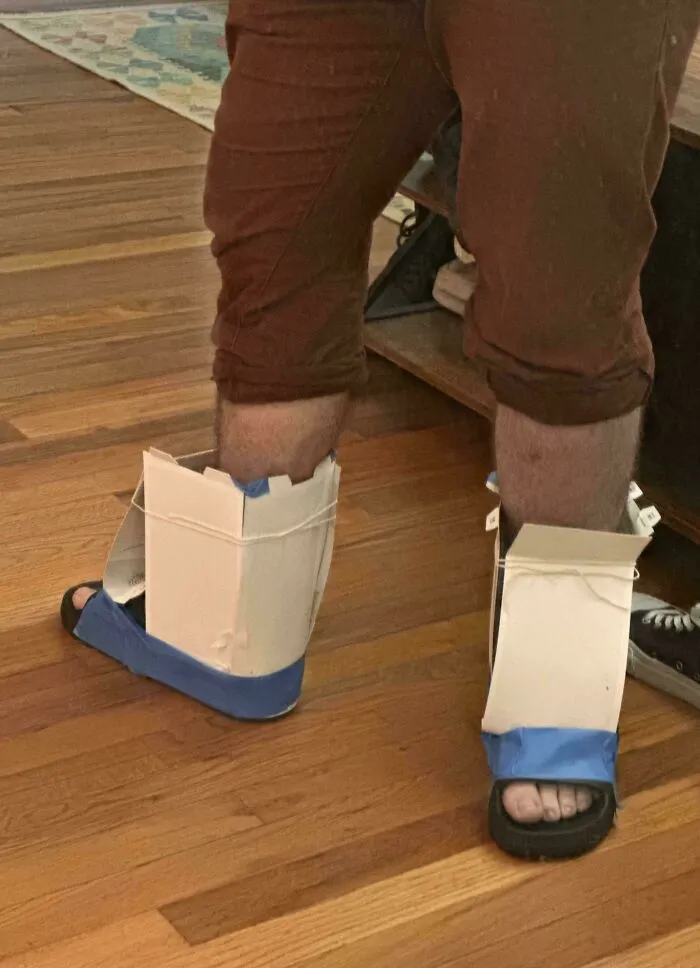 Homemade cardboard and tape footwear on person’s feet demonstrating redneck engineering creative MacGyvering.