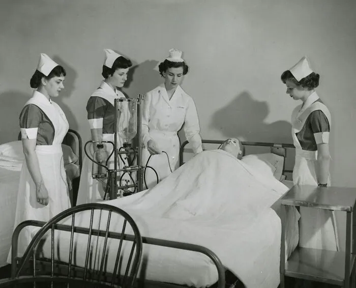 Vintage nurses in traditional uniforms caring for a patient in a hospital bed, showcasing healing and hope.