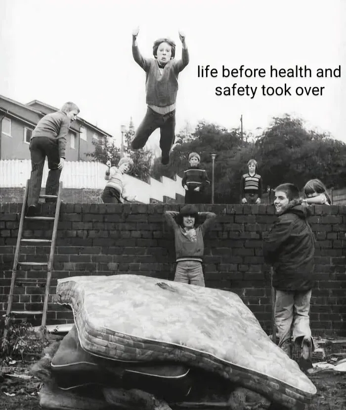 Kids jumping from a wall onto stacked mattresses outdoors, nostalgic posts capturing the magic of growing up in the ’90s.