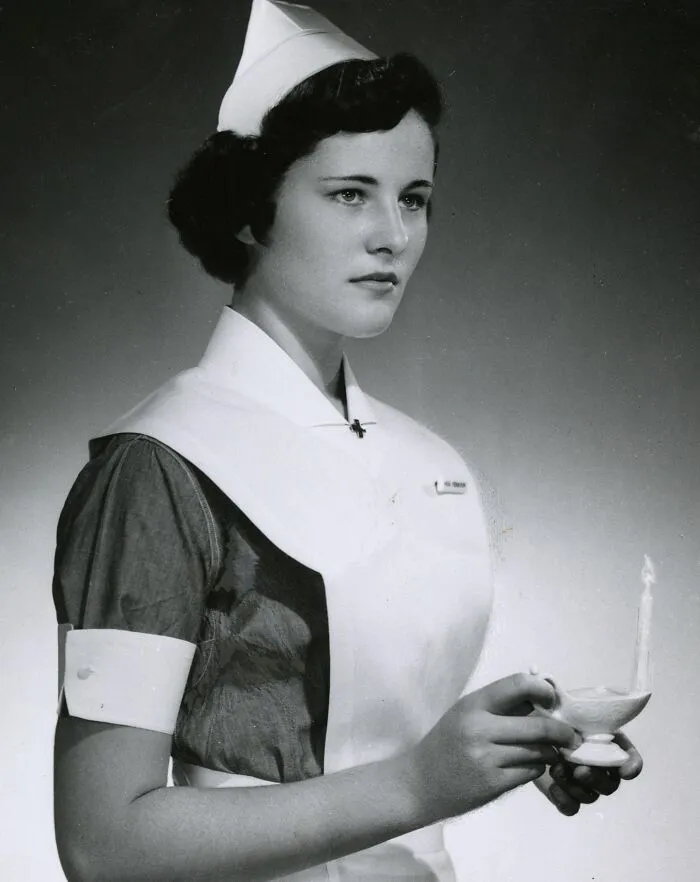 Vintage photo of a nurse holding a lit lamp, embodying healing and hope in classic nurse uniform.