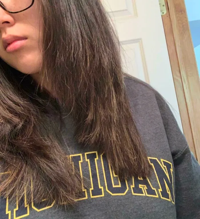Person with uneven haircut and straight dark hair showcasing a salon glow-up gone wrong experience.