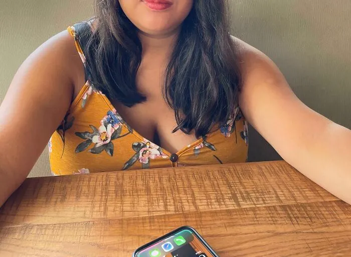 Mujer decepcionada en salón de belleza vistiendo blusa amarilla con flores, mostrando expresión de arrepentimiento.
