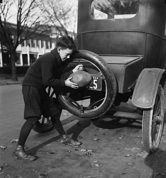 "Flat Spare Tires Are Numerous Around Washington These Days Due To The Youthful Football Players Who Have Found An Easier Way To Inflate The Pigskin Than Using Their Lungs. 'Billy' Friel Shown Inflating His Football.", Washington, D.C., 1924
