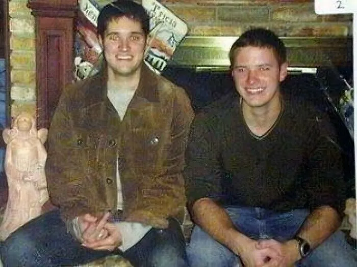 Two young men sitting in front of a fireplace, part of photos with terrifying and horrific backstories series.