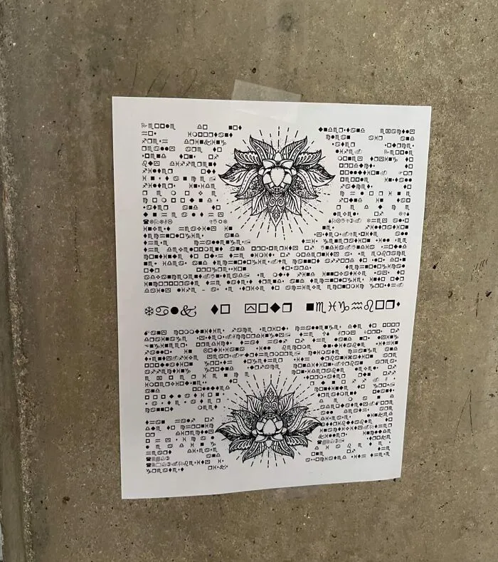Sheet of paper with cryptic symbols and floral designs taped to a concrete wall, illustrating interesting mysteries that still baffle people.