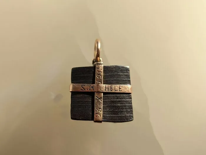 Antique black square pendant with gold cross detailing, a beautiful old thing treasured by its owner.