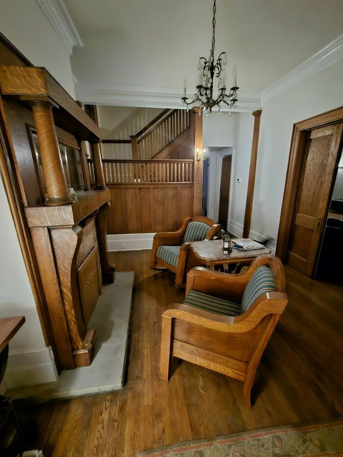 Vintage wooden chairs and fireplace in a cozy living room showcasing beautiful old things people enjoy owning.