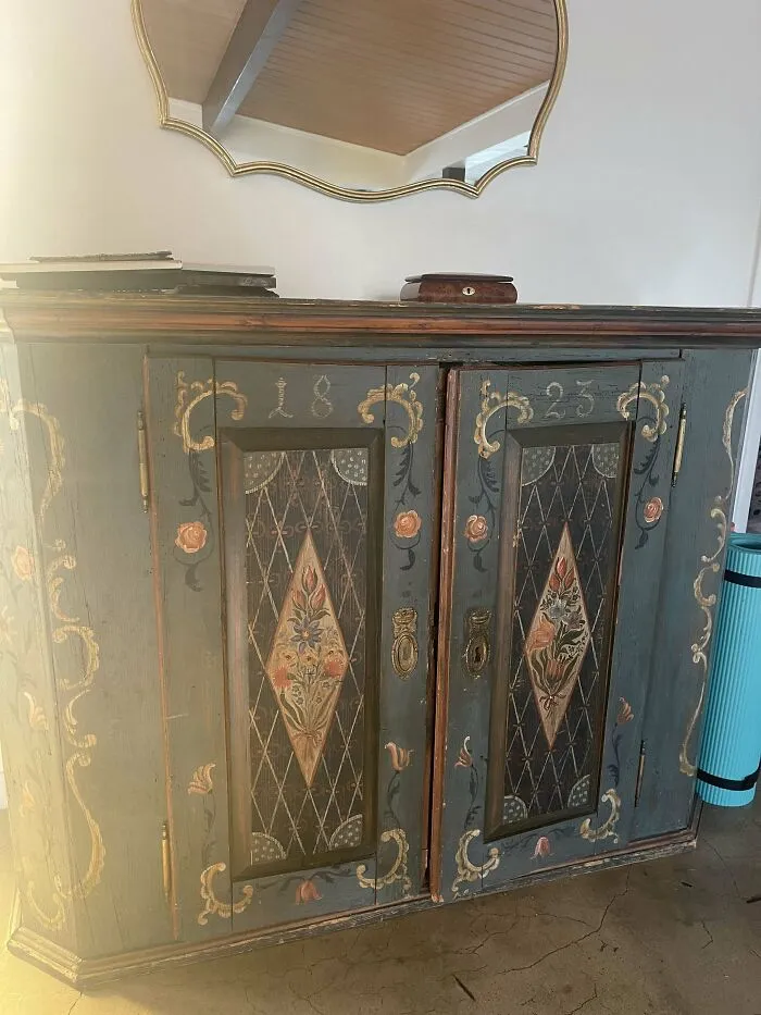 Antique painted wooden cabinet with floral designs and vintage decorative details, showcasing beautiful old collectible furniture.