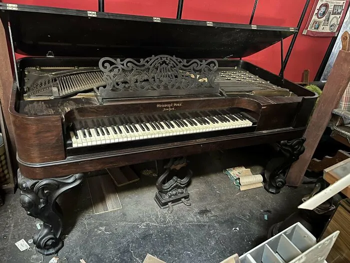 Antique ornate wooden piano with intricate detailing and visible strings, showcasing a beautiful old vintage instrument.