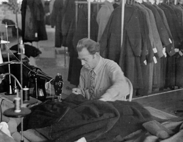 Man sewing coats in a garment factory, showcasing labor and industry in Great Depression photos.