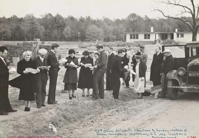 Group of people reading distributed literature during the Great Depression at a rural homestead in 1936.