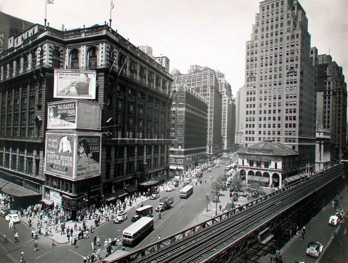 Black and white Great Depression photo showing bustling city streets with vintage buses and tall buildings.