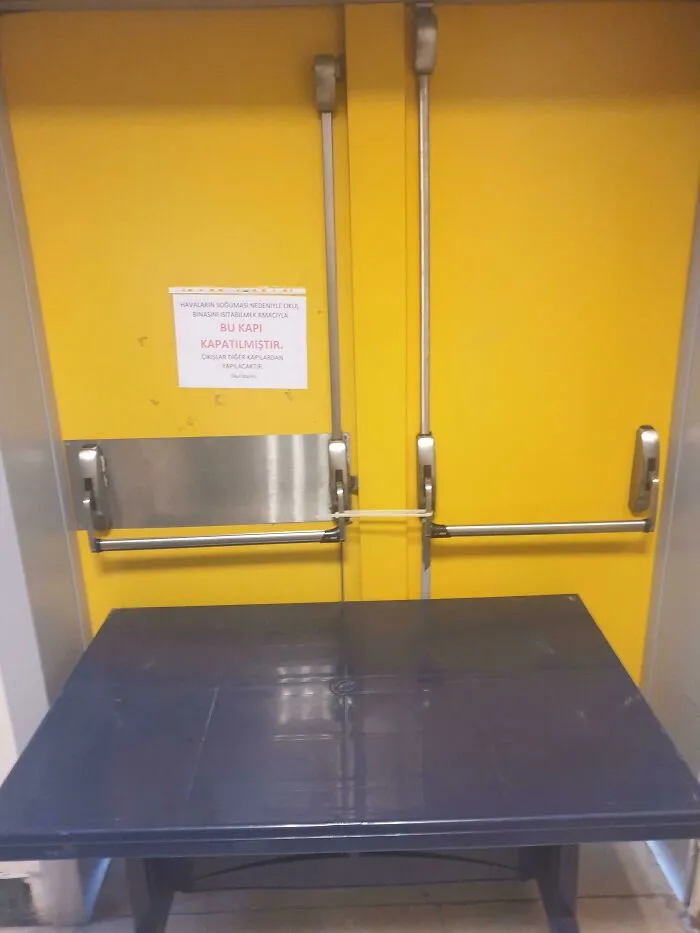Yellow emergency exit door blocked by a table, illustrating schools not always being equal or great in safety measures