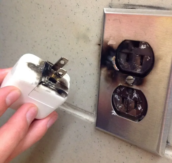 Burnt electrical outlet and charger plug in a school setting, highlighting unsafe conditions in some schools.