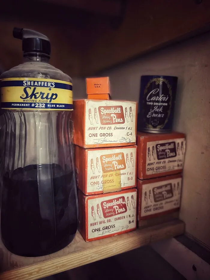 Botella y cajas de tinta y plumas antiguas mostrando la vida cotidiana en la década de 1950.