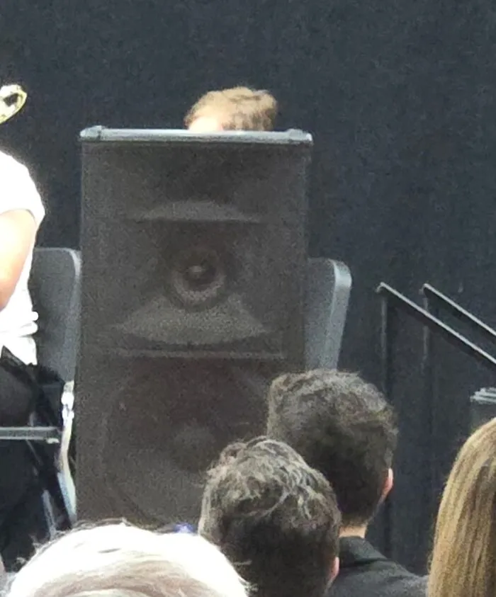 Person's head hidden behind large speaker during a school event highlighting schools are not created equal.