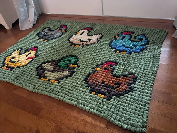 Crochet enthusiasts made an incredible green textured blanket featuring colorful pixelated bird designs on wooden floor.