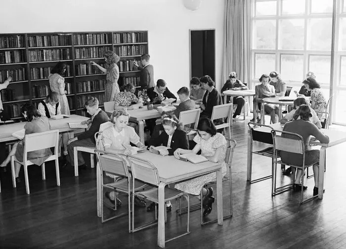 Students reading and selecting books in a quiet school library during World War II, showcasing schools worldwide in this era.