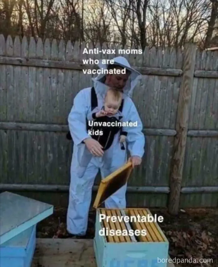 Person in protective suit labeled anti-vax moms holding a child labeled unvaccinated kids near a hive labeled preventable diseases.