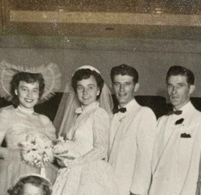 Vintage candid glimpse of a bride and groom with wedding party members in classic mid-20th century attire.