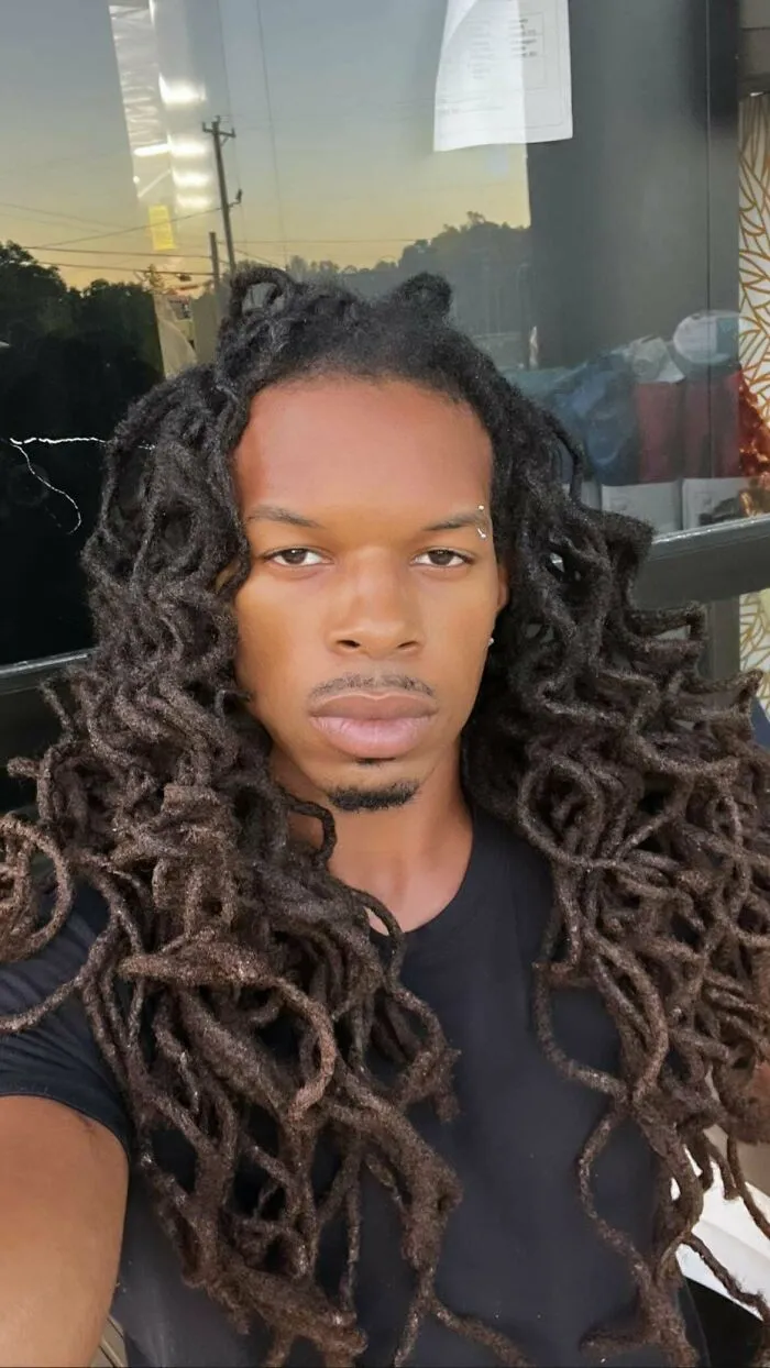 Young man with fierceflow beautiful hair men style wearing a black shirt outdoors at sunset