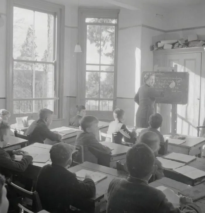 Classroom scene showing students and teacher during World War II in a historic school setting worldwide.