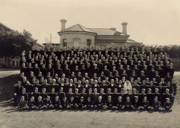 Large group of students and staff posing for a formal school photo outdoors during World War II era.