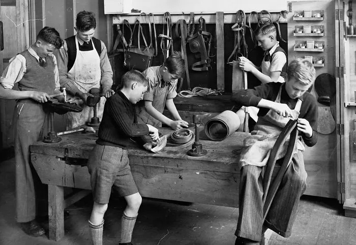Boys working on leather craft projects in a classroom workshop at a school during World War II.
