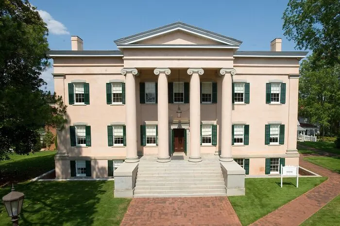 Historic home with classical columns and green shutters, representing America’s architectural heritage.