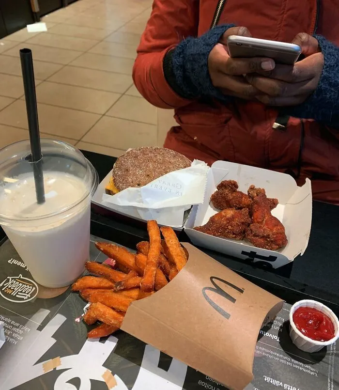 Persona usando teléfono móvil mientras disfruta detalles ingeniosos de comida rápida en varios países del mundo.