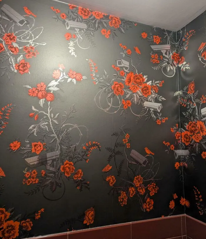 Papel tapiz con flores naranjas y cámaras de seguridad impresas, un fallo sorprendente en hoteles y alojamientos.