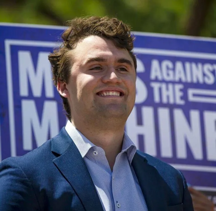 Young man in a blue suit smiling outdoors during a public event, illustrating there was an attempt moment.