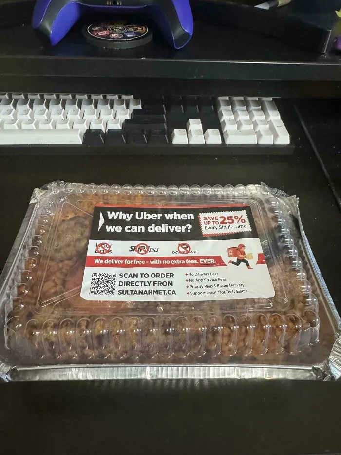 Takeout container with label promoting delivery service as a moderately interesting alternative to Uber Eats on a desk.