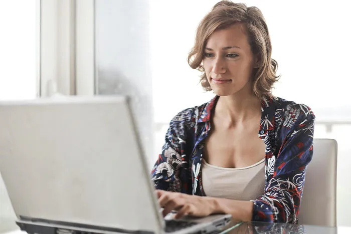 Woman using laptop indoors, reflecting on microfeminisms and social dynamics involving big burly men.