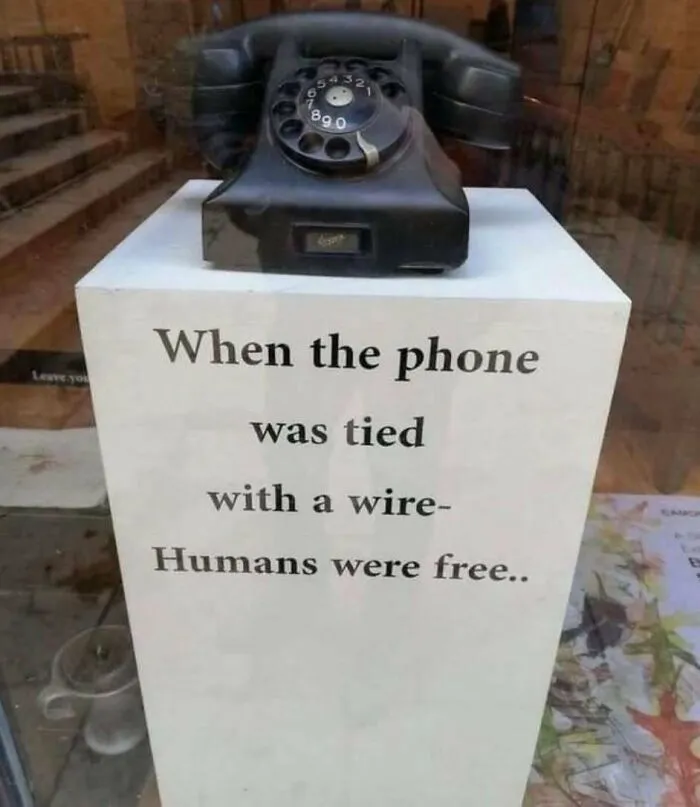 Vintage rotary phone displayed with a sign reflecting on the good old days of the 1980s and wired phone use.