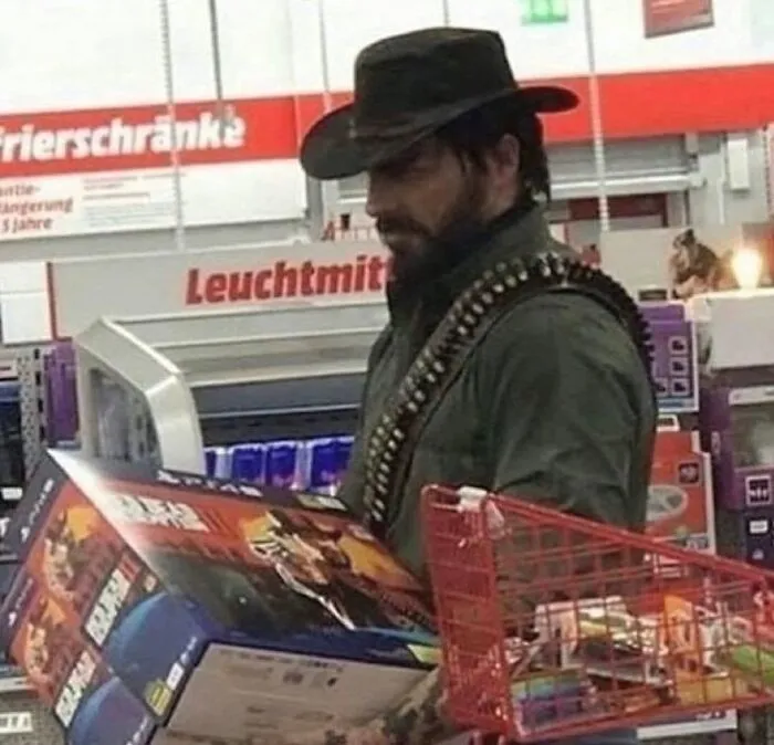 Man dressed as a cowboy holding a video game box in a store, an unusual scene that makes no sense but draws attention.