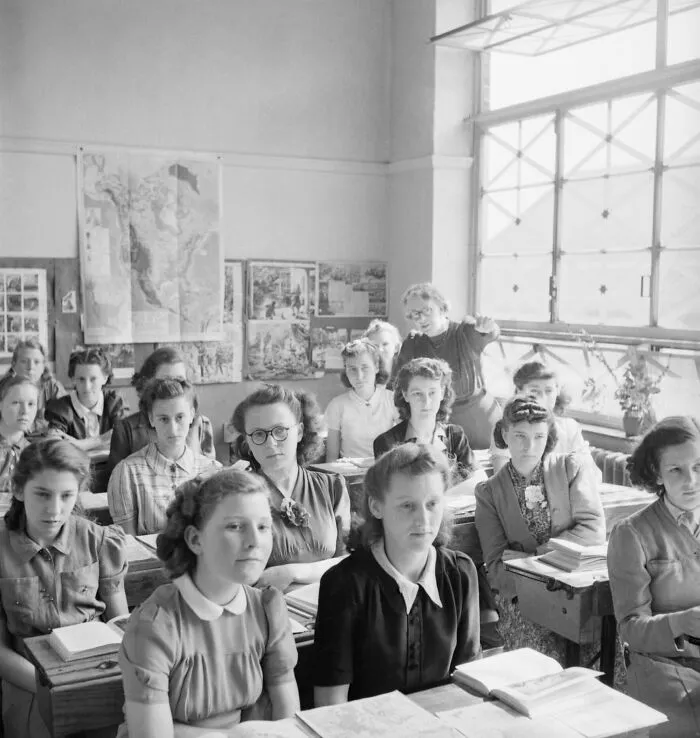 Students attentively seated in a classroom during World War II, showcasing schools worldwide in a historic learning setting.