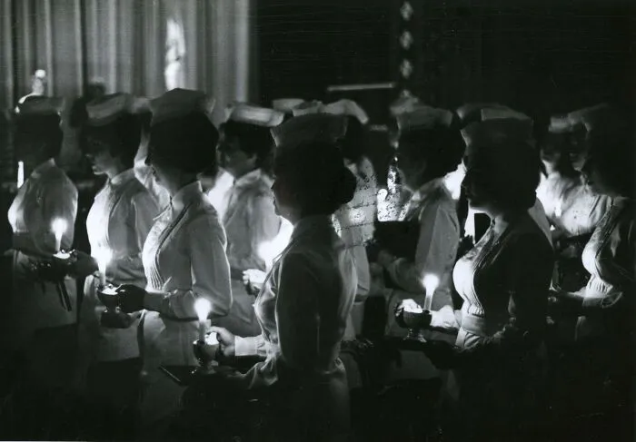 Vintage nurses holding candles in a ceremonial setting, reflecting hope and healing during a historical moment.